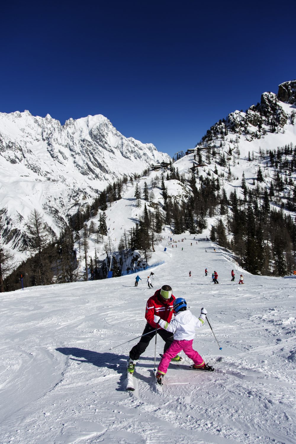 A ski instructor teaches a kid how to ski in Courmayeur