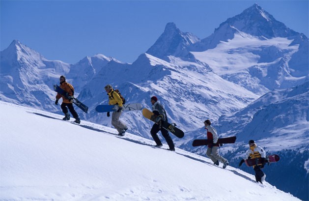 A group of boarders hiking up for getting a grand descent down the slopes of Crans-Montana. 