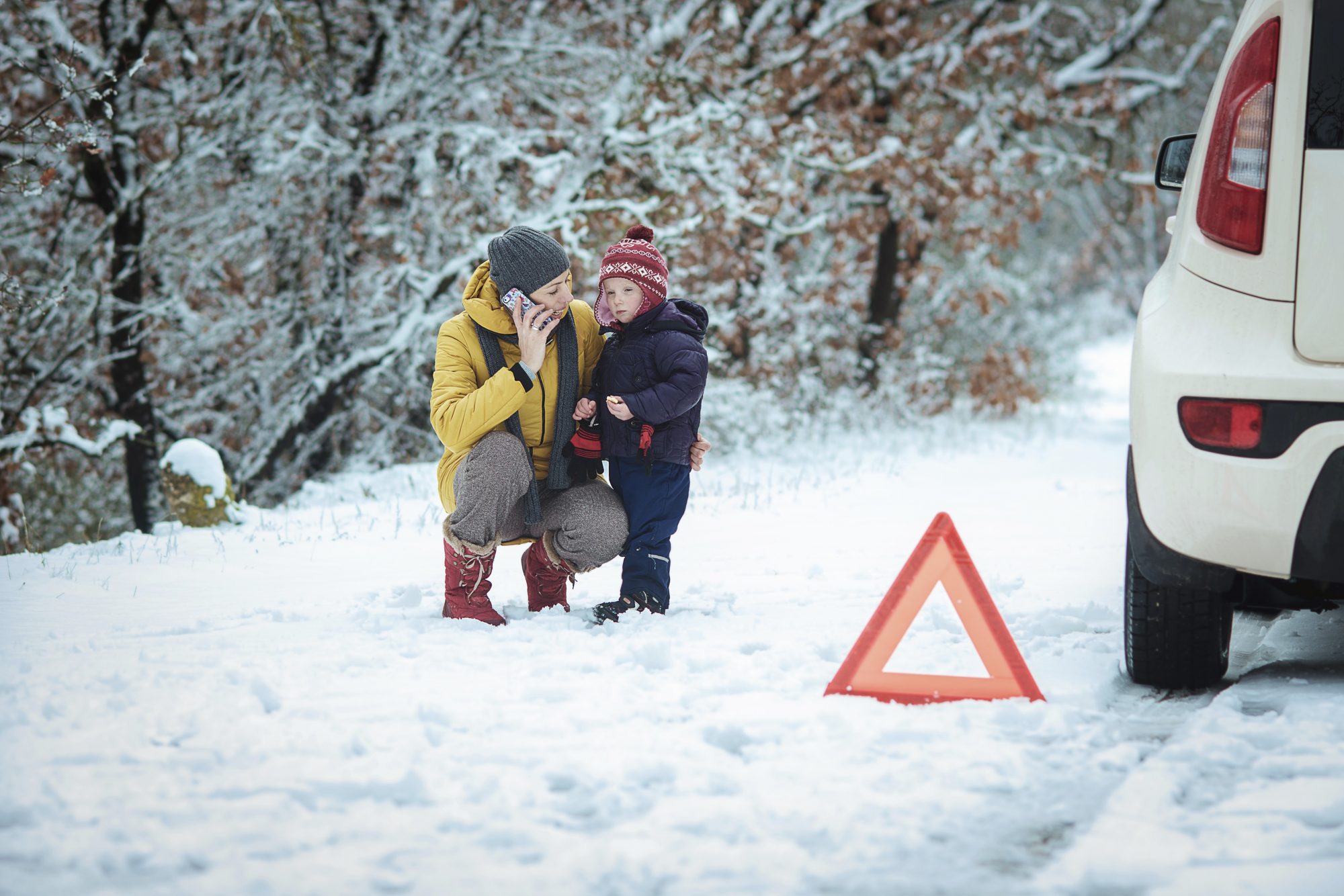 A woman with a child on the winter road. emergency sign. Skiers Face Winterisation and Ski Rack Charges Adding up to £179 On Car Hire Bill.  Photo: iCarhireinsurance.com