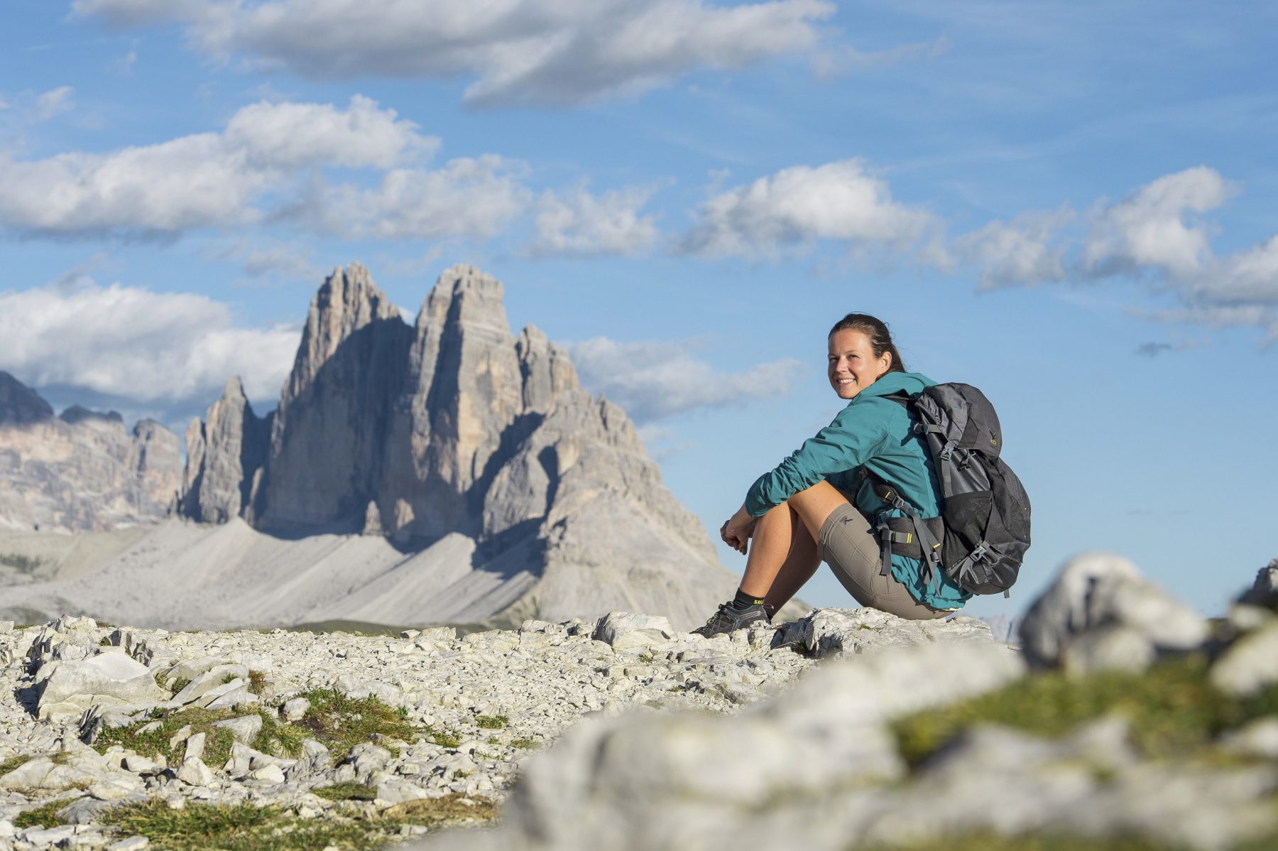 Copyright: IDM South Tyrol / Thomas Grüner. A woman having a break with a view. From the homecoming cross there is a beautiful view of the famous mountain range of the Three Peaks.
