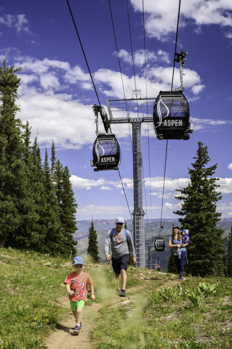 A family hiking under the Silver Queen Gondola in Aspen. Photo: Aspen Skiing Company. Aspen Snowmass is opening for the Summer Season.